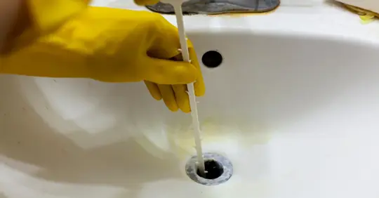 Homeowner using a drain auger